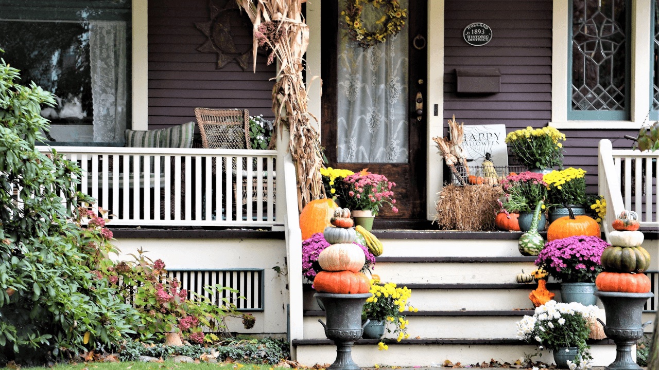 Front porch steps decorated for fall with pumpkins, gourds and potted mums